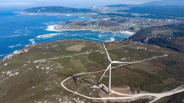 Aerial view of a large wind farm situated on a coastal landscape in Portugal, with turbines spinning gracefully. The scene is bathed in the golden light of either sunrise or sunset, enhancing the sense of clean energy production.