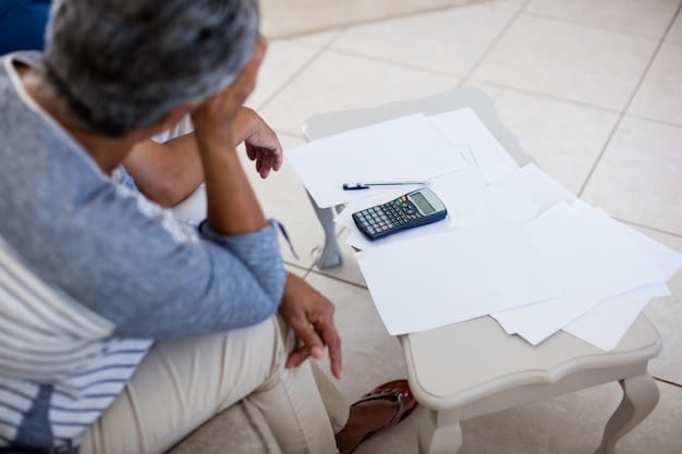 A person using a calculator to budget their finances, with documents showing bills and income statements spread across the table.
