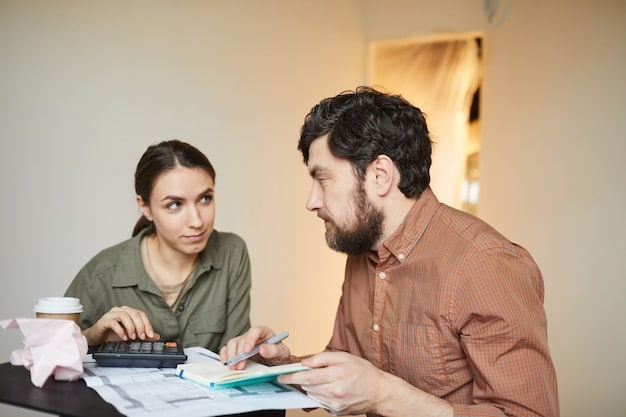 A close-up image of a financial advisor explaining mortgage options to a young couple in their office. The advisor is pointing to a chart illustrating different interest rates and payment schedules.