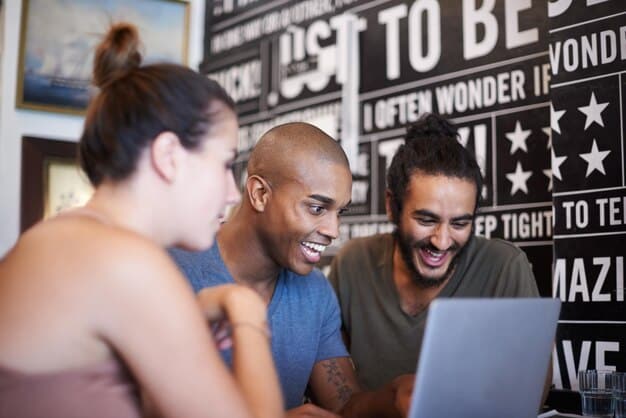 A diverse group of young adults looking at stock market data on a large screen in a co-working space, with expressions of excitement and collaboration.