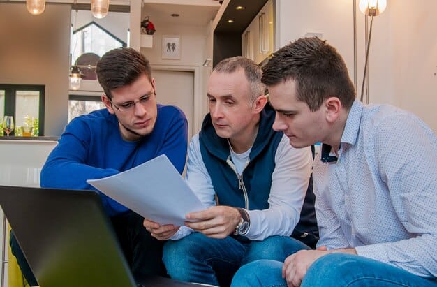 A group of people collaborating around a table, reviewing financial documents and data related to real estate investments. The atmosphere is professional and focused.