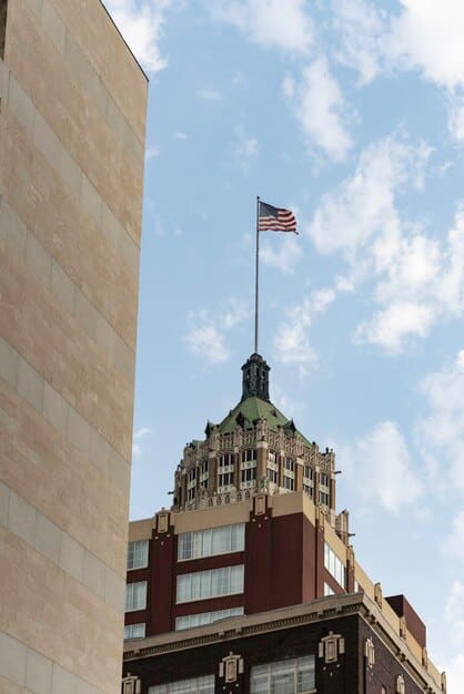 A close-up shot of a central bank building, with focus on the entrance and flags waving in the wind. The sky is overcast, creating a serious and institutional atmosphere.